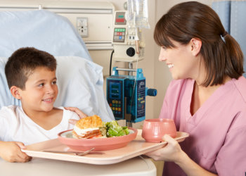 nurse giving food to her child patient