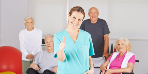 caregiver and group of elderly smiling